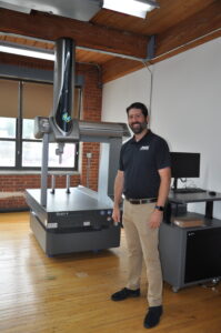 Picture of Mack Prototype President Greg Cebular posing with the Company’s new Hexagon Global S7.10.7 Scan Plus Coordinate Measuring Machine (CMM).